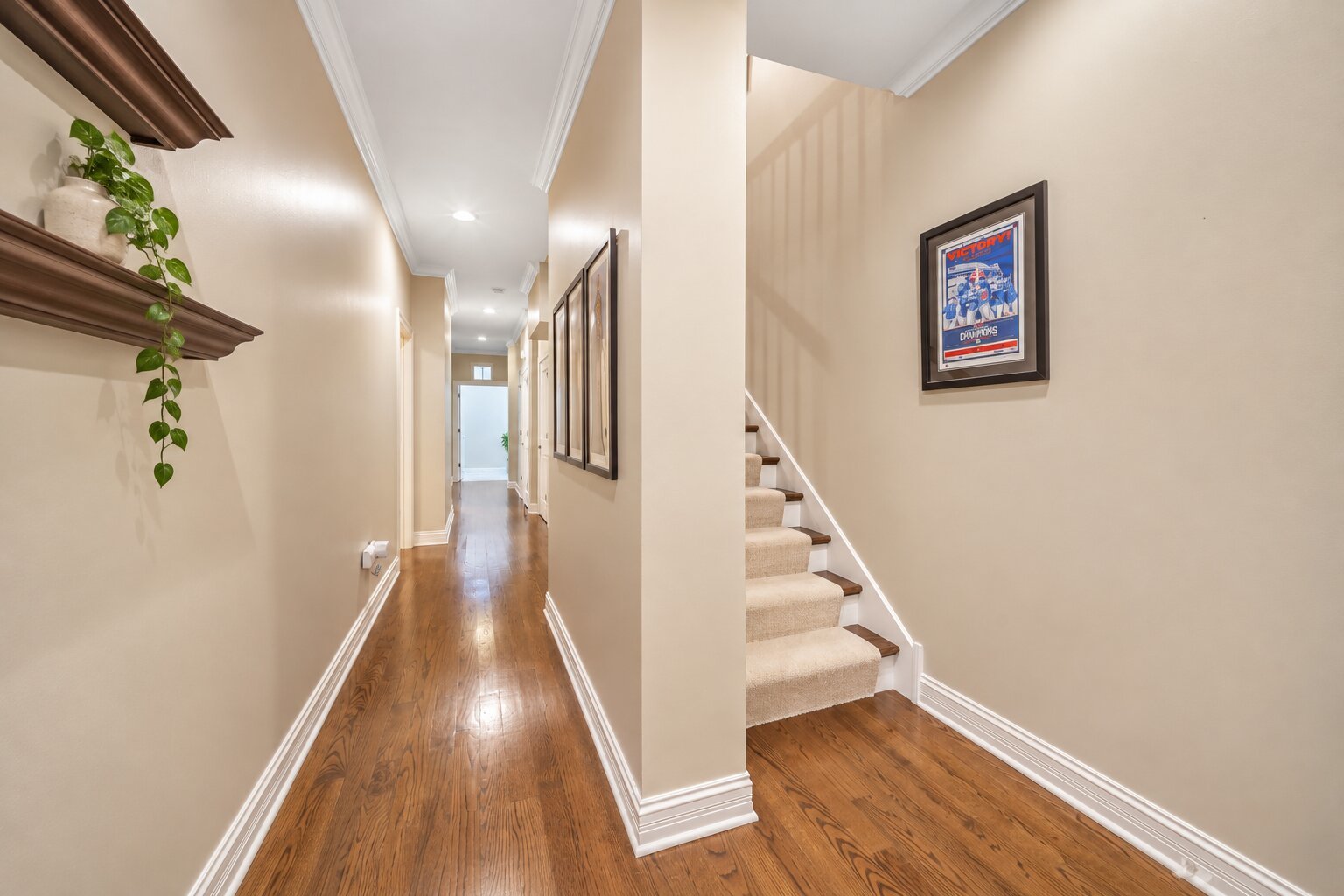 Hallway with polished hardwood floors, built-in shelves, and a carpeted staircase.