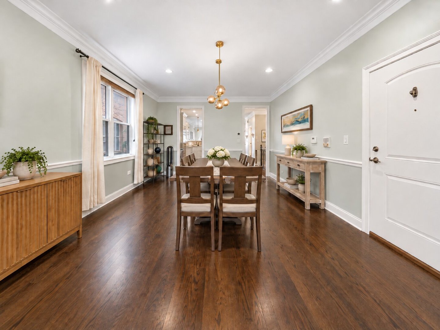 Dining room with a wood table, dark hardwood floors, tall curtained windows, and a brass pendant light.