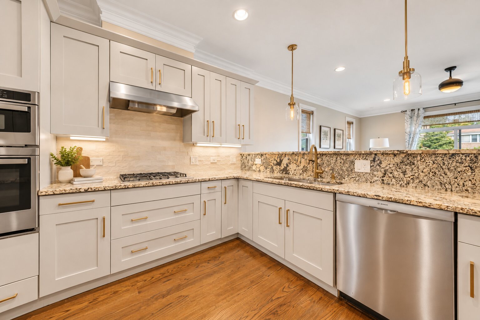 Bright kitchen with white shaker cabinets, patterned stone counters, stainless steel appliances, and hardwood floors.
