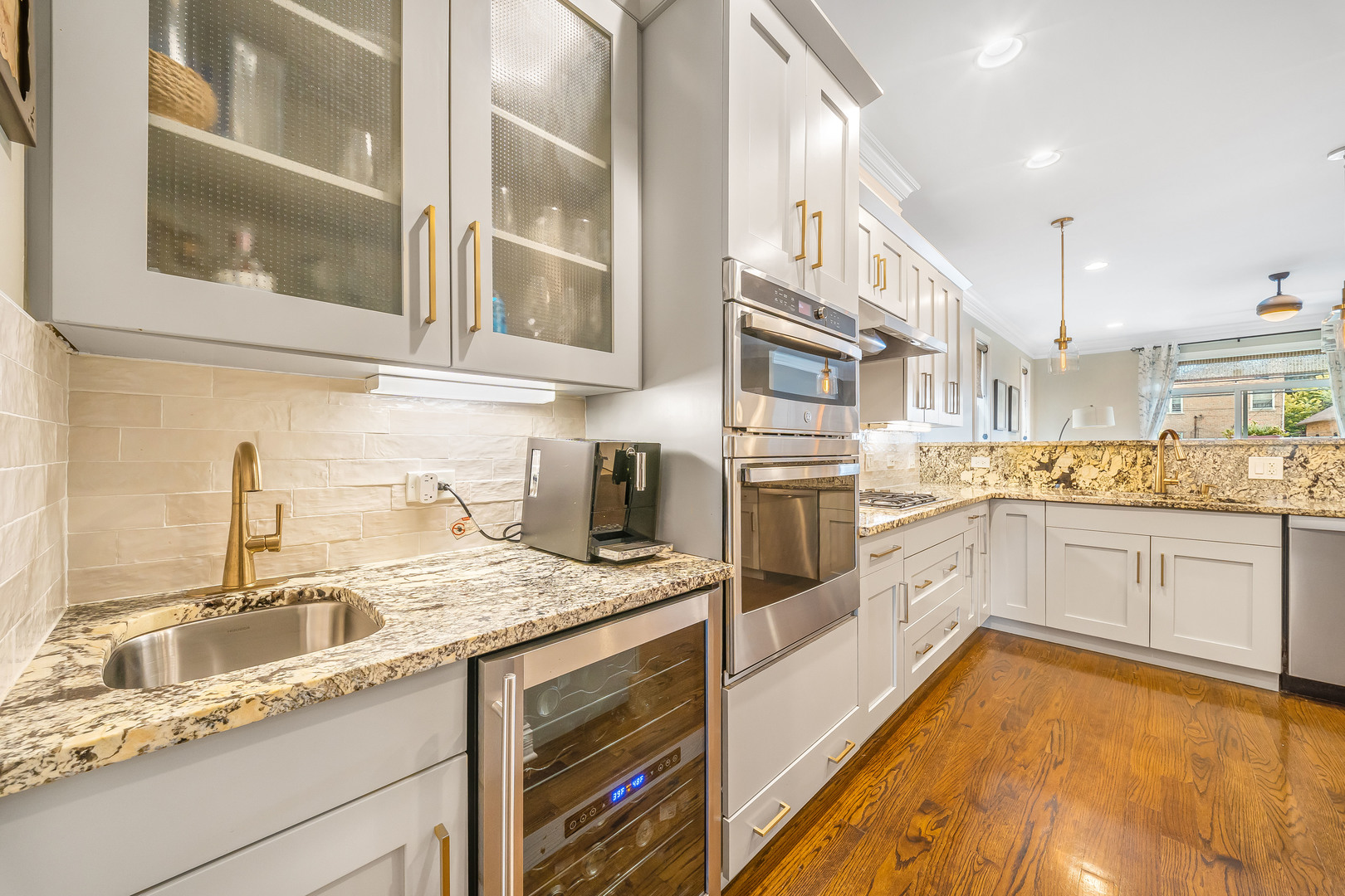 Renovated kitchen with white cabinets, patterned stone counters, stainless steel appliances, and wood floors.