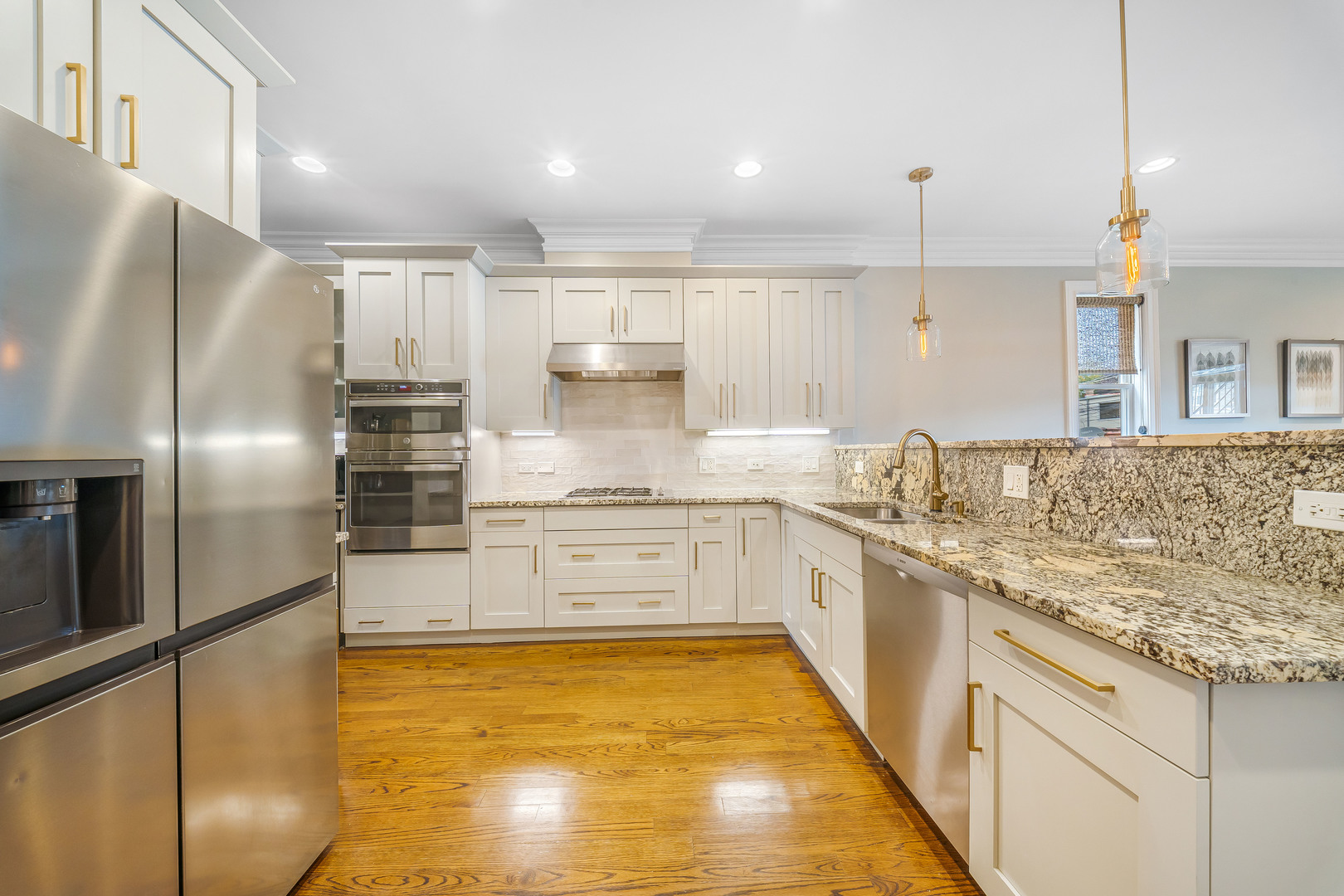 Renovated kitchen with white cabinets, stainless steel appliances, granite counters, and warm hardwood floors.