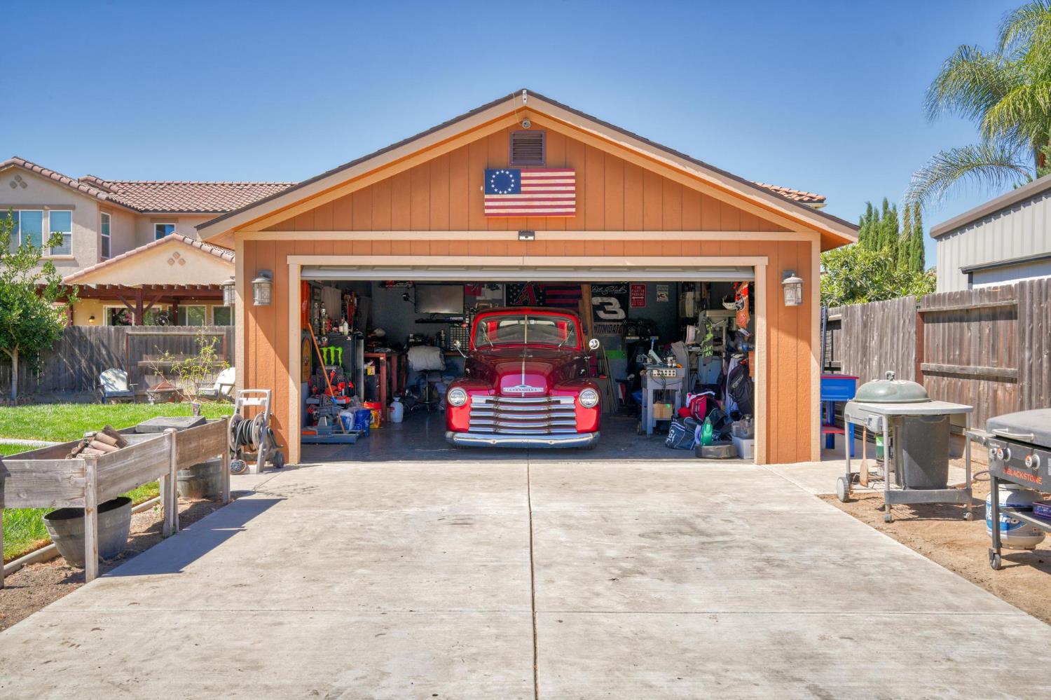 Detached garage with an open workshop and red vintage pickup truck inside.