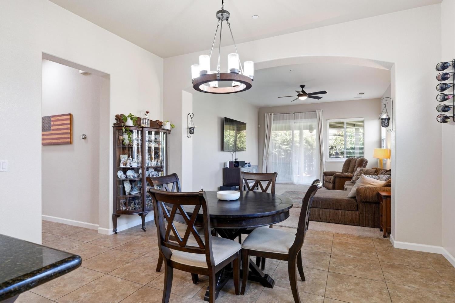 Dining room with a round dark table and chandelier opening into a furnished living room.