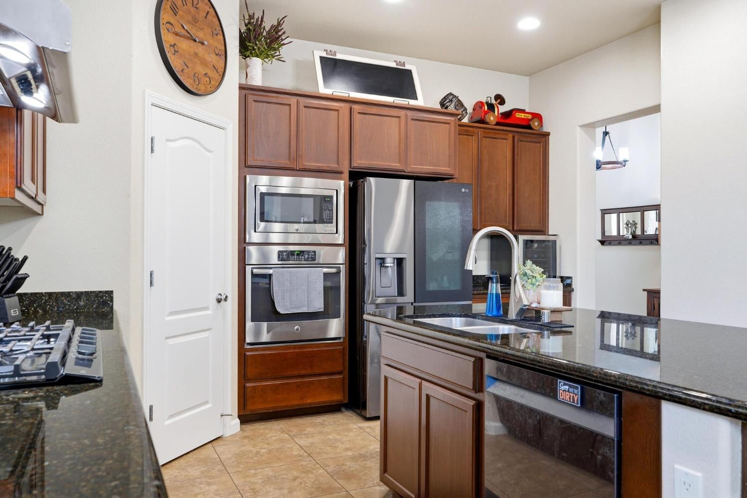 Kitchen with dark wood cabinets, granite counters, a large sink island, and stainless steel appliances.
