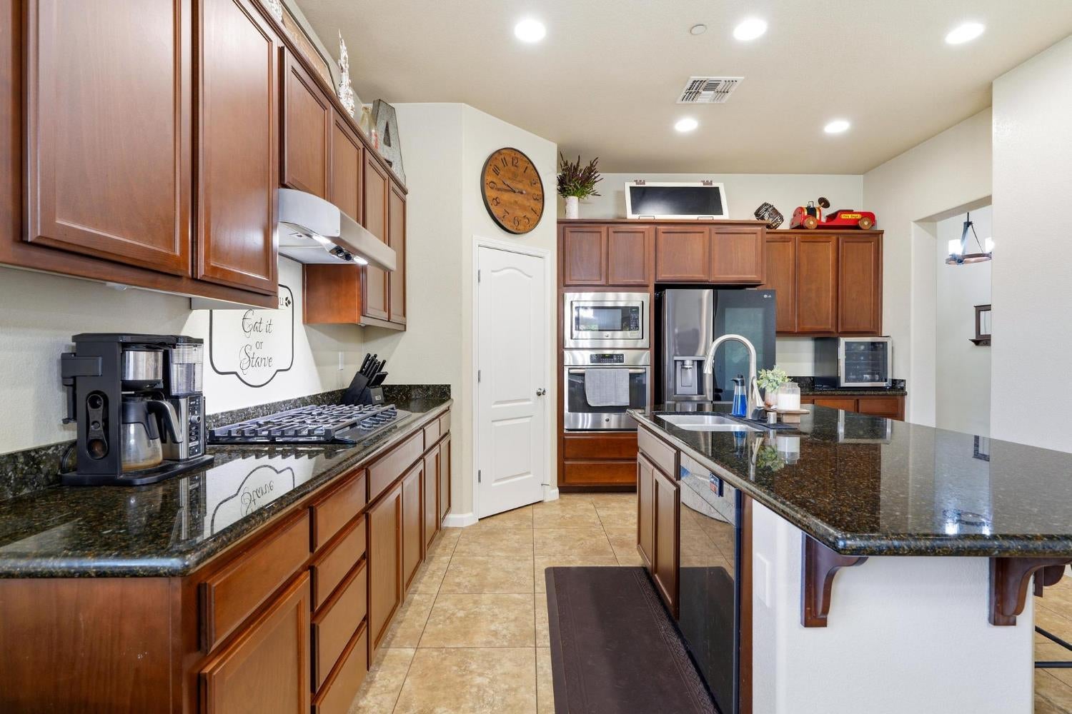 Kitchen with wood cabinets, dark granite counters, a large island, and stainless steel appliances.