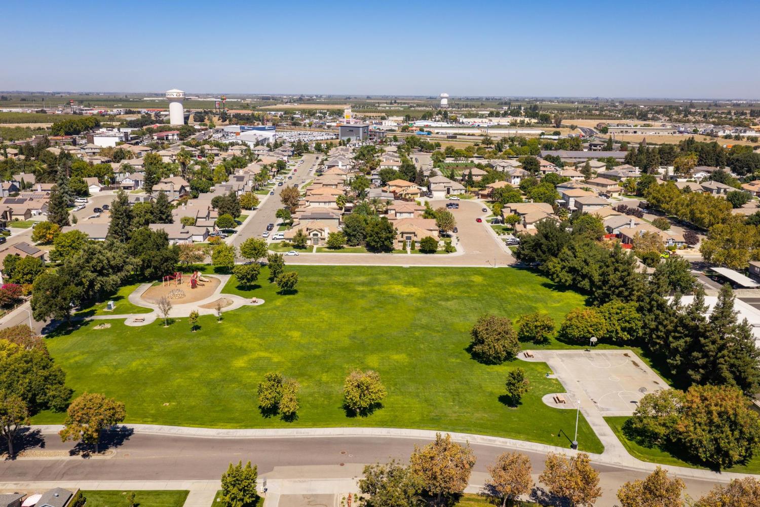 Aerial view of homes beside a large green park with a playground and basketball court.