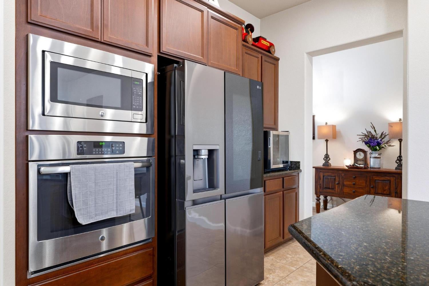 Kitchen with wood cabinetry, stainless steel appliances, and a dark stone countertop.