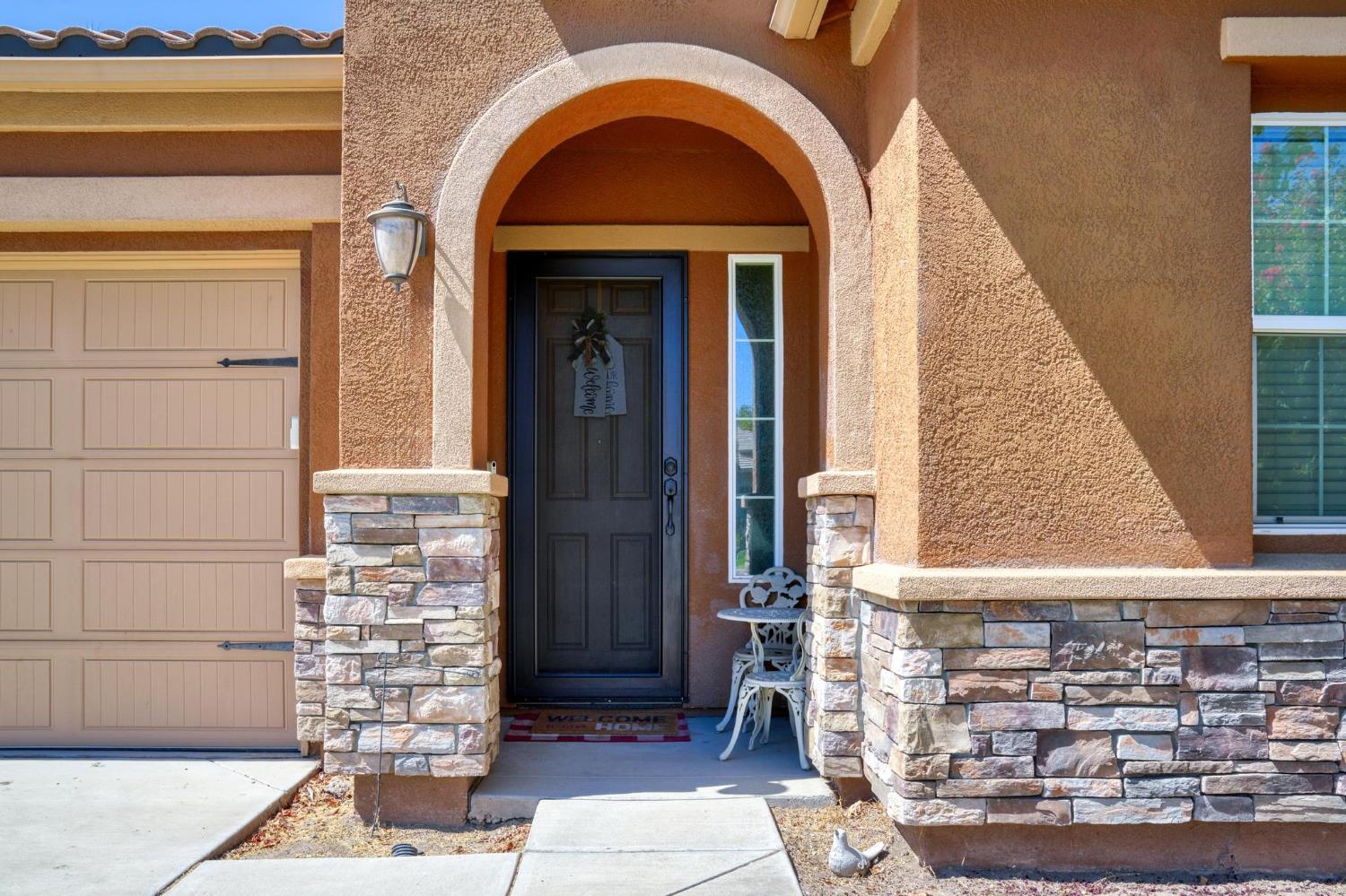 Home entry with a large arched porch, stone columns, and dark front door.