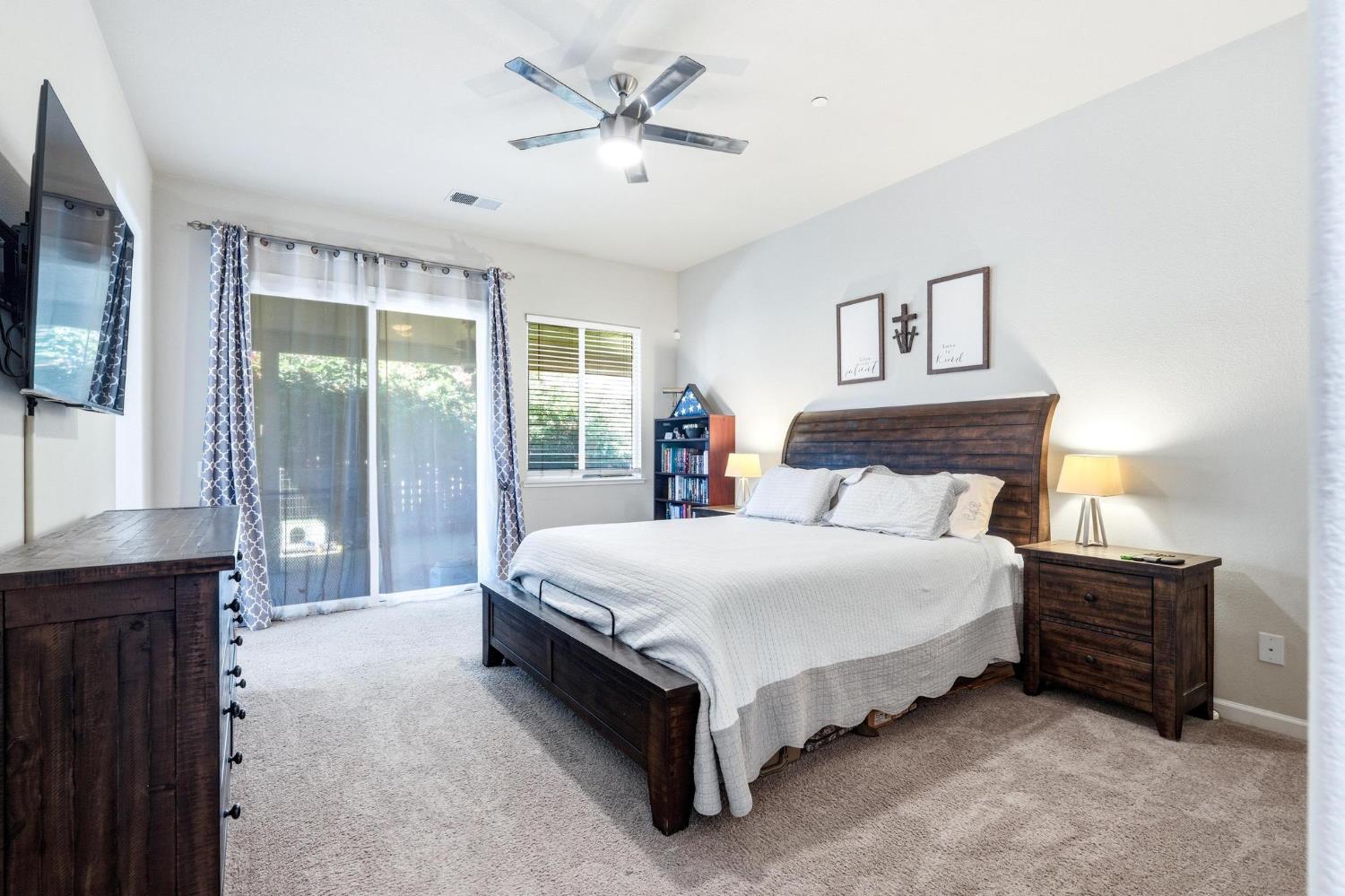 Bedroom with a dark wood bed, white bedding, matching nightstands, and sliding glass doors.