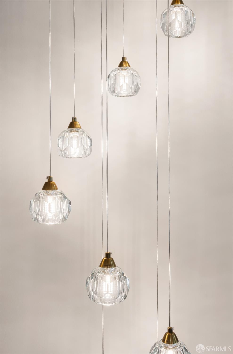 Cascading pendant lights with faceted glass shades and brass-colored caps.