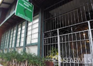 Building facade with barred entrance, tall gridded windows, and a green sign.