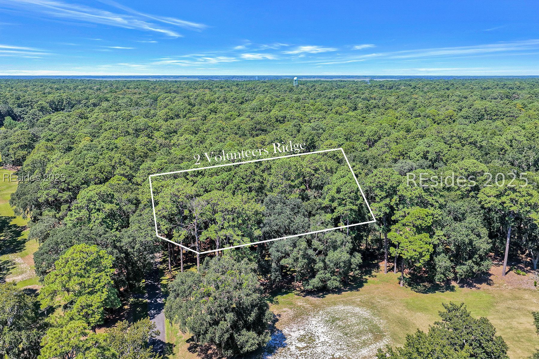 Aerial view of a wooded parcel outlined among dense forest and open grass.