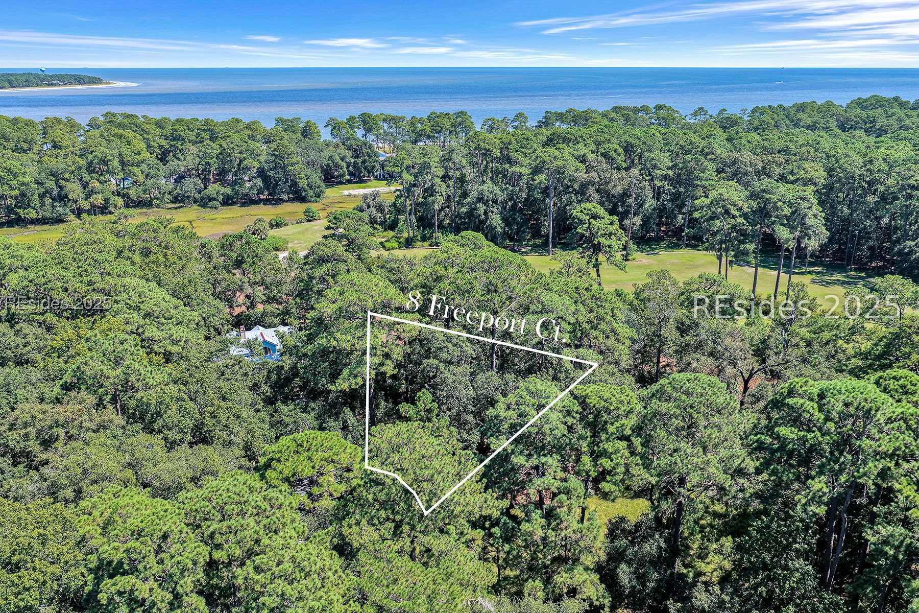 Aerial view of wooded 8 Freeport Court parcel, outlined in white, with the ocean beyond the trees.