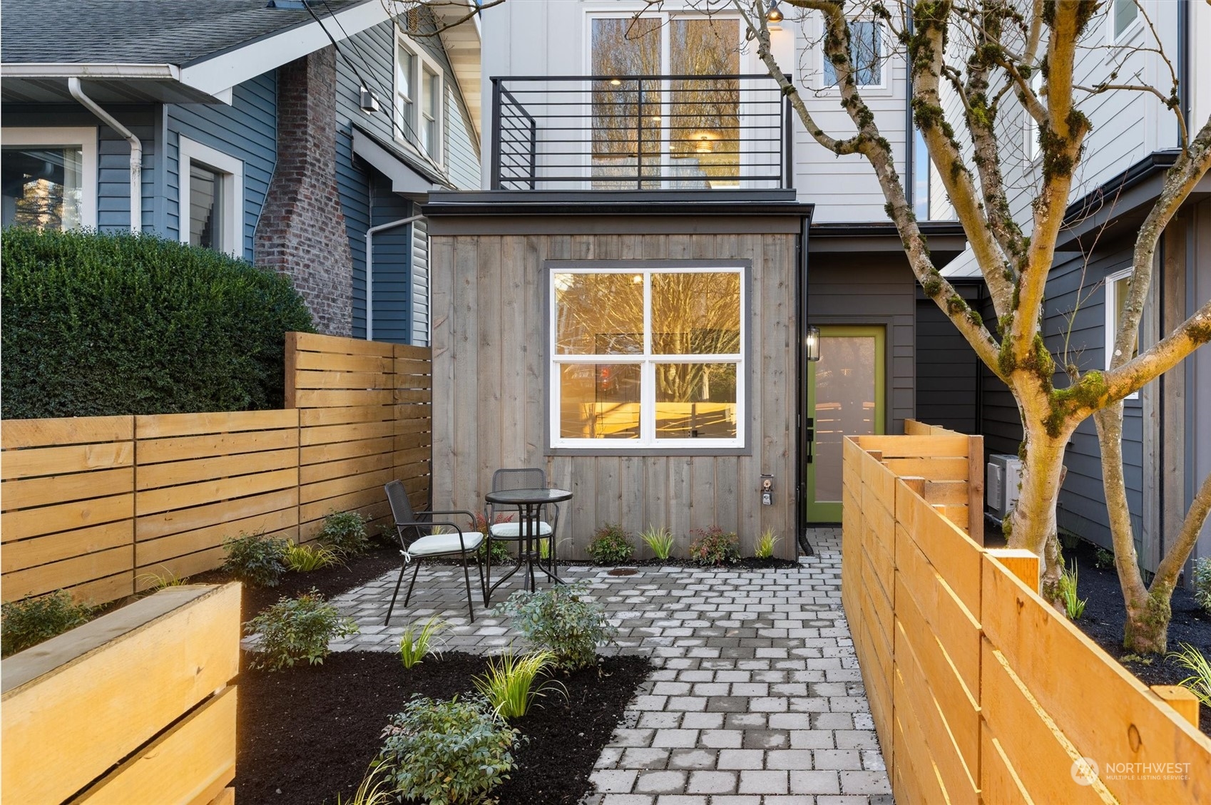 Modern home courtyard with a paved patio, cedar fencing, and outdoor seating.