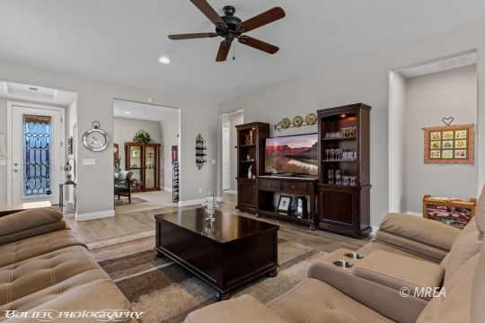 Living room with tan leather seating, a dark coffee table, and a wooden entertainment center.