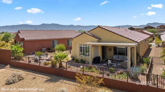 Home’s rear covered patio and fenced desert-landscaped yard, with mountains in the distance.