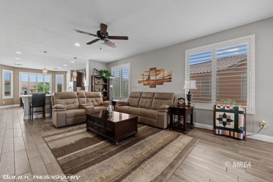 Living room with two reclining sofas, a striped rug, and large windows with blinds.