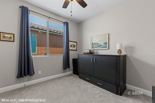 Bedroom with a dark Murphy bed cabinet, gray carpet, and a window with blue curtains.