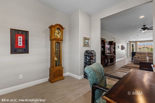 Furnished living room with a wooden grandfather clock and an adjoining sitting area.