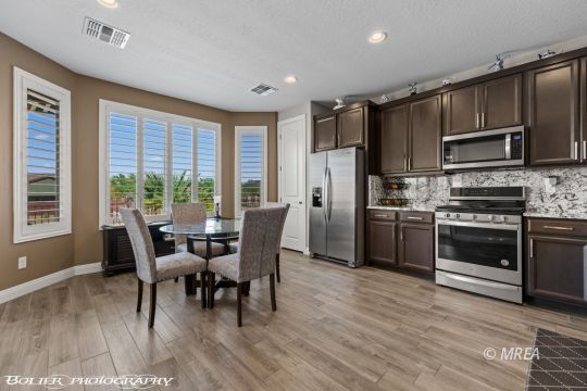 Kitchen and dining area with dark cabinetry, stainless appliances, and a window-side table.
