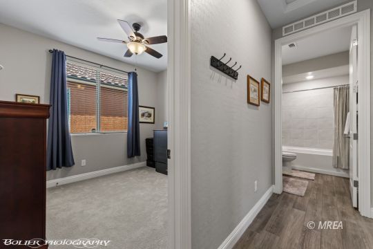 Hallway connecting a bedroom and bathroom, with blue curtains and a tiled bathtub surround.