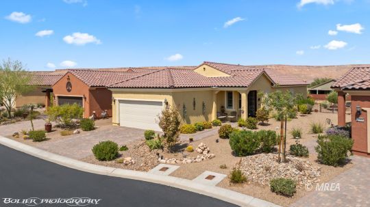 Single-story stucco home with a tile roof, two-car garage, and desert landscaping.