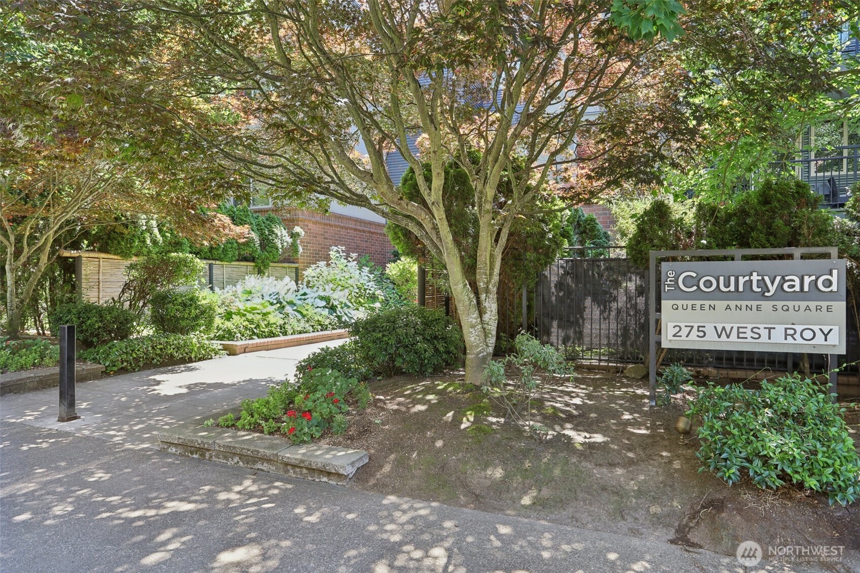 The Courtyard entrance at Queen Anne Square, with a 275 West Roy sign beneath mature trees.