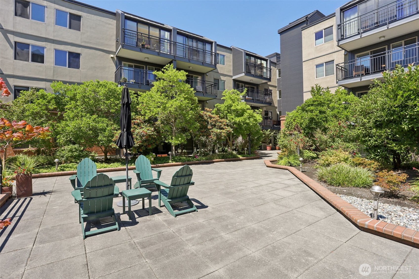Apartment courtyard with green Adirondack chairs, landscaped beds, and balconies above.