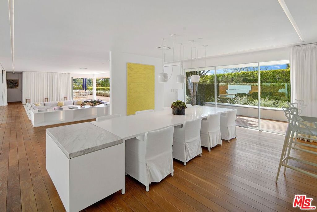 Open-plan kitchen and dining area with a long white island and garden-facing glass doors.