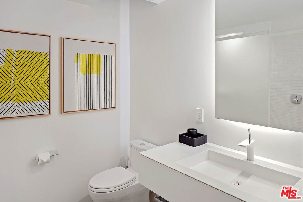 Modern bathroom with a white vanity, integrated sink, and framed yellow geometric artwork.