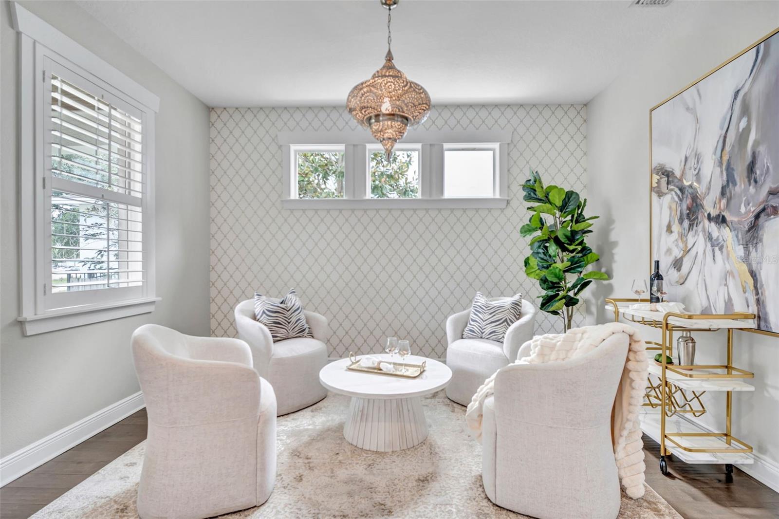 Staged sitting room with white chairs, patterned wallpaper, and a round coffee table.