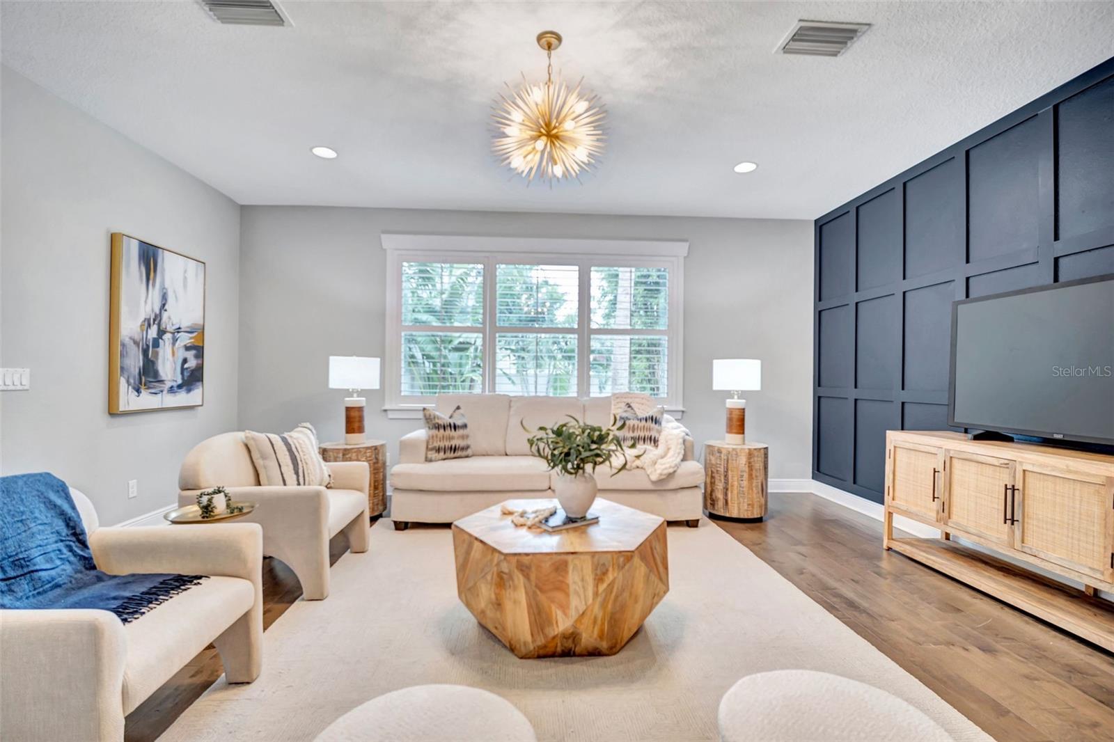 Staged living room with cream sofas, a geometric wood coffee table, and navy paneled accent wall.