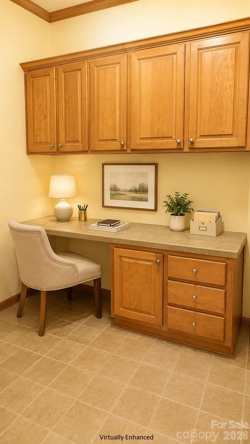 Home office nook with a tiled desk, extensive wood cabinetry, and a beige upholstered chair.