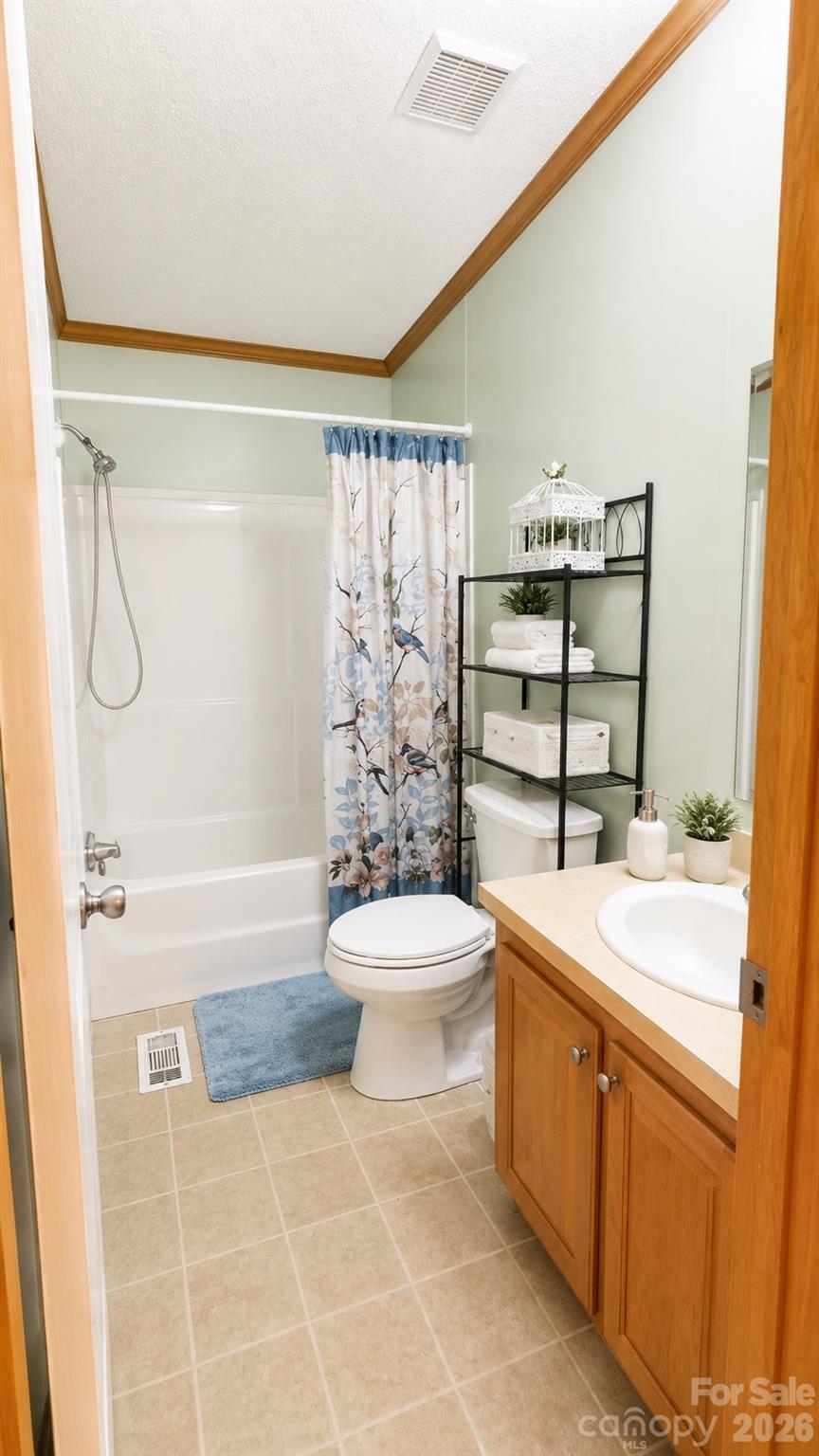 Bathroom with a floral shower curtain, black shelving, and a wood vanity.