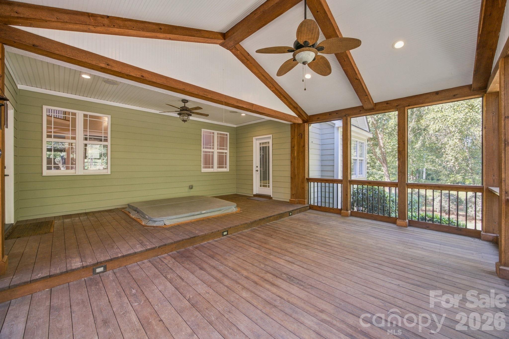 Screened porch with timber ceiling beams, a raised deck, and a recessed hot tub.