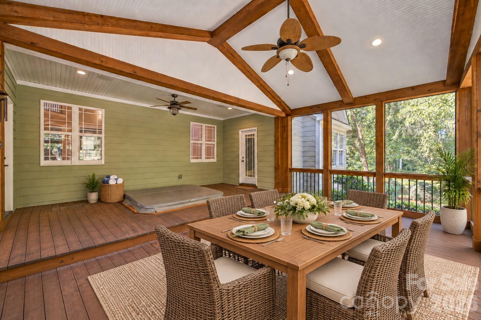Screened porch with timber beams, a set dining table, wicker chairs, and a hot tub.