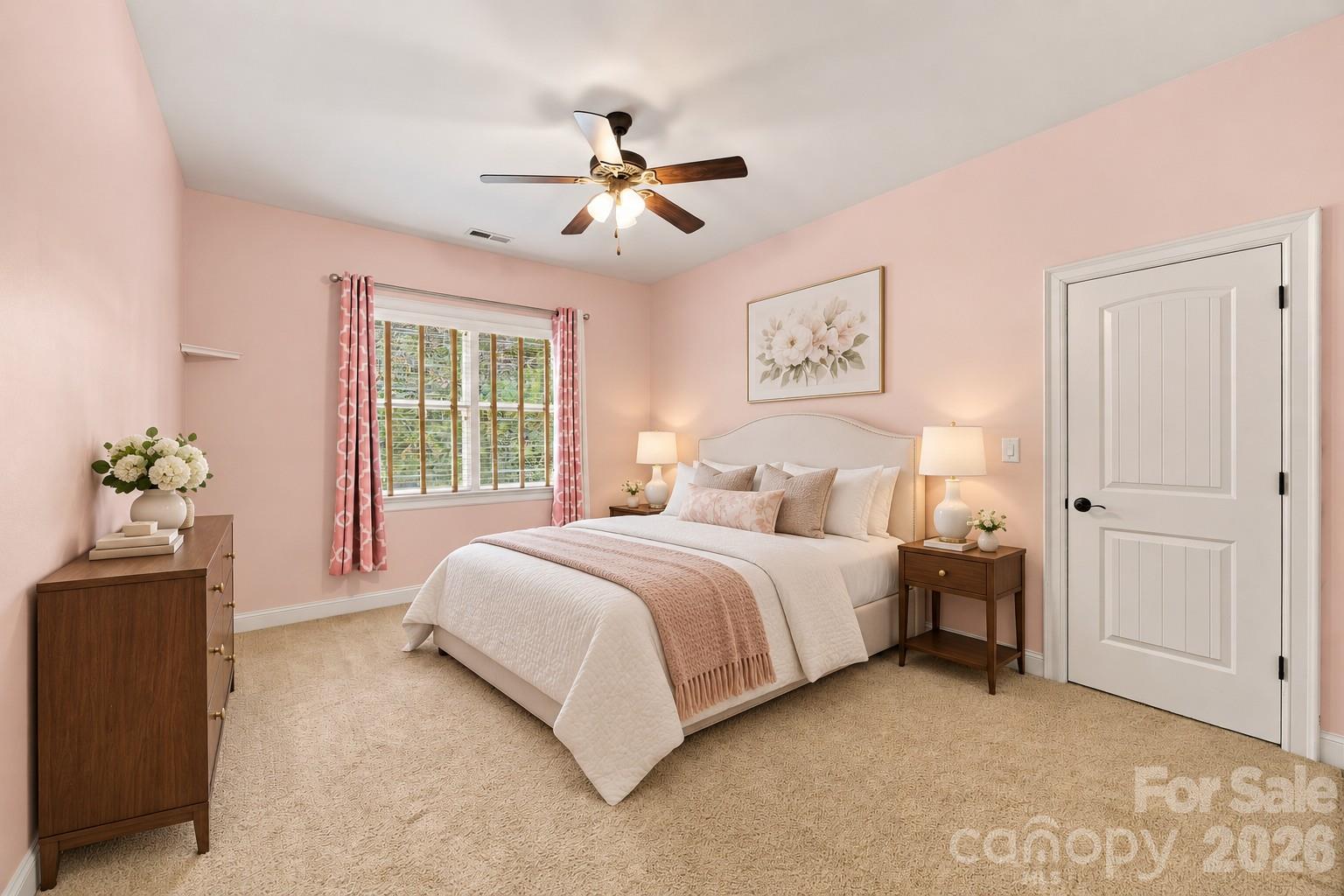 Furnished bedroom with pink walls, blush bedding, a curtained window, and a ceiling fan.