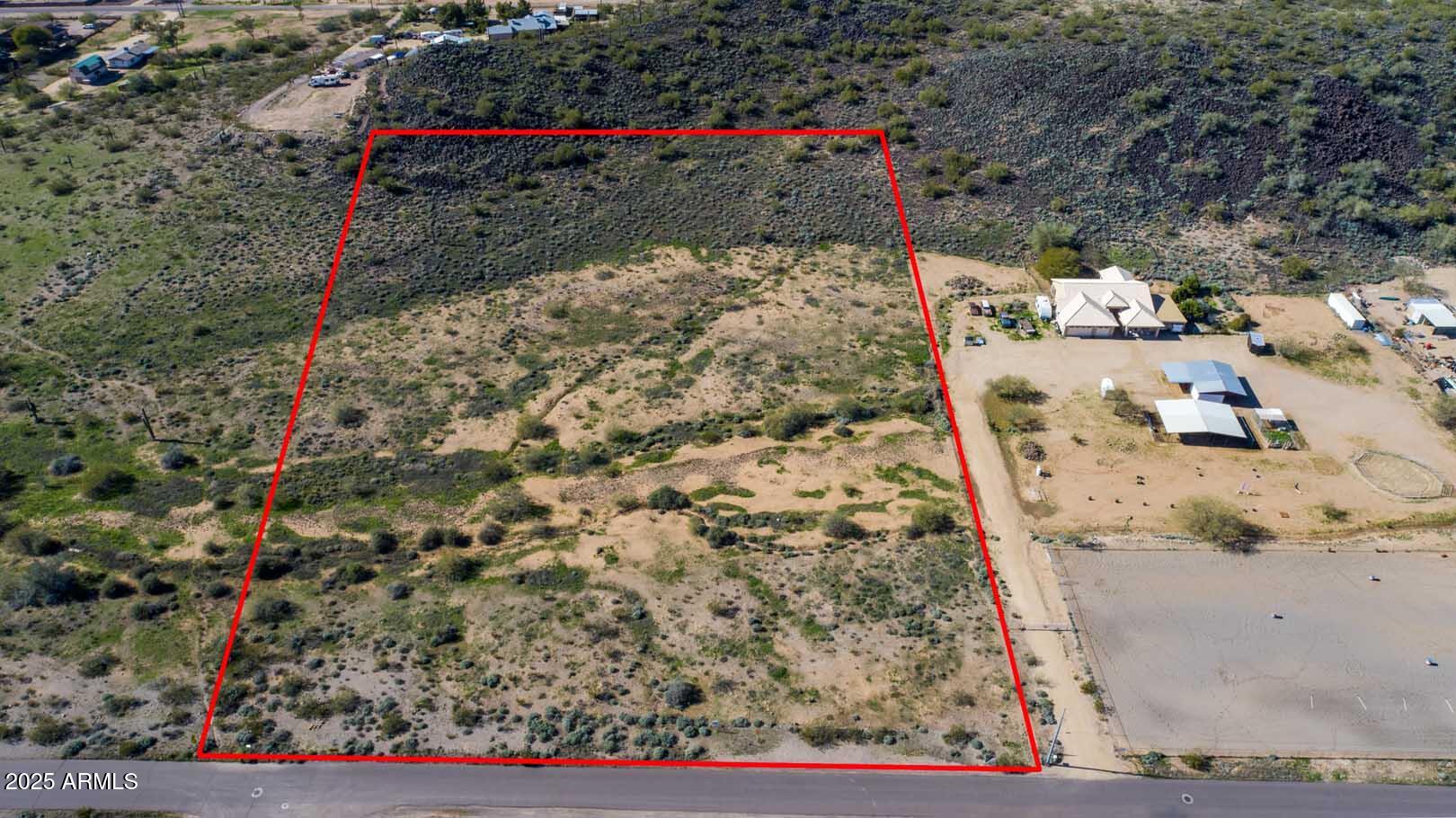 Vacant desert parcel outlined in red, with sparse scrub and road frontage.