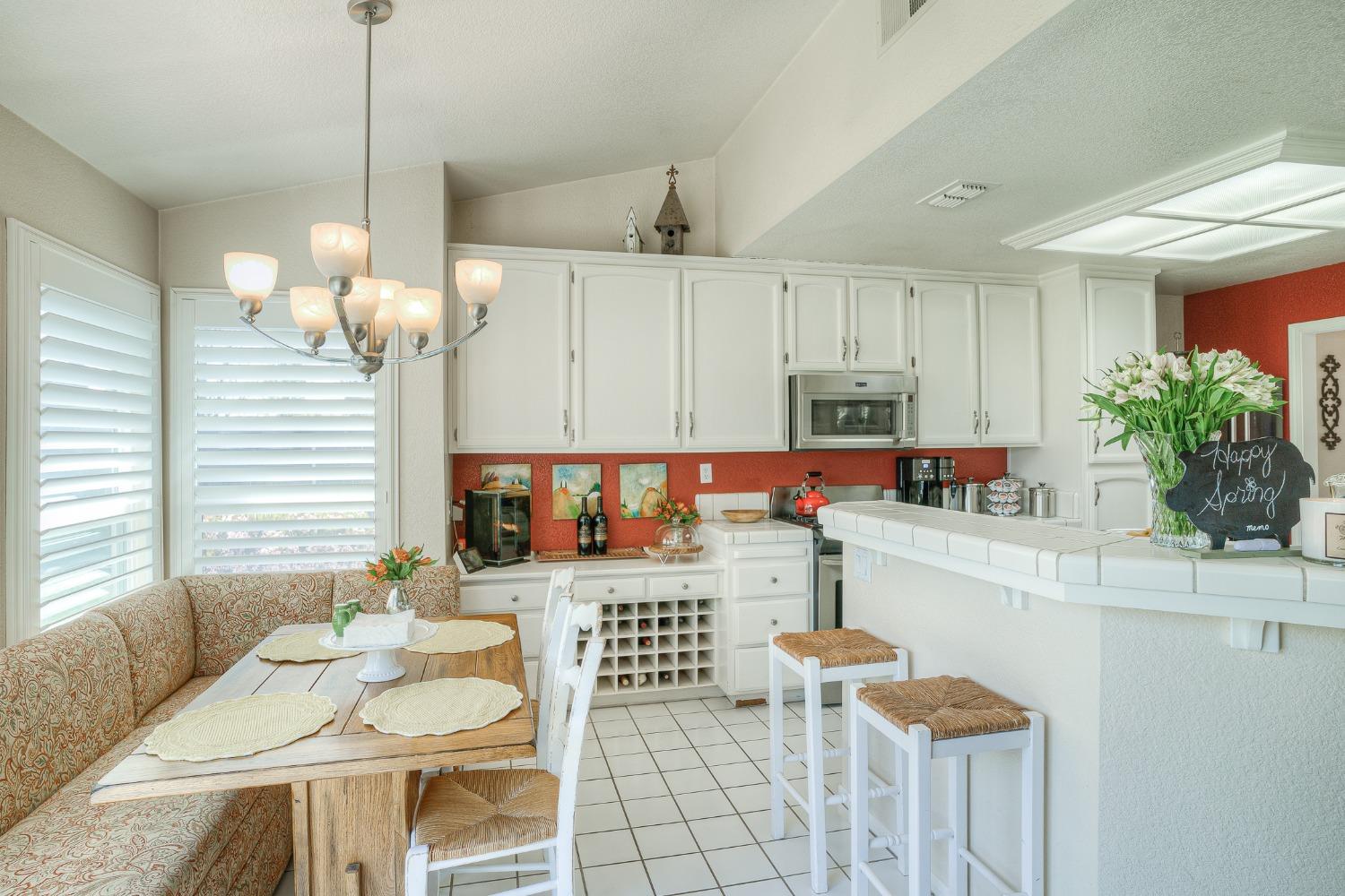 Kitchen with white cabinets, red backsplash, breakfast bar, and dining nook.