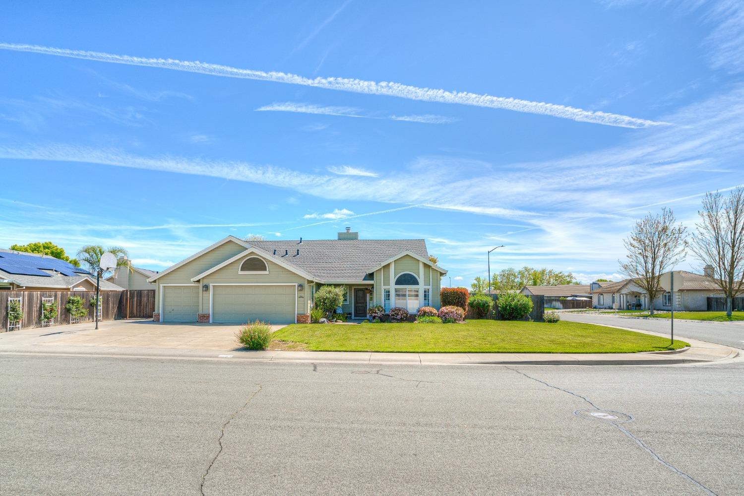 Single-story home with a two-car garage, arched windows, and a landscaped front lawn.