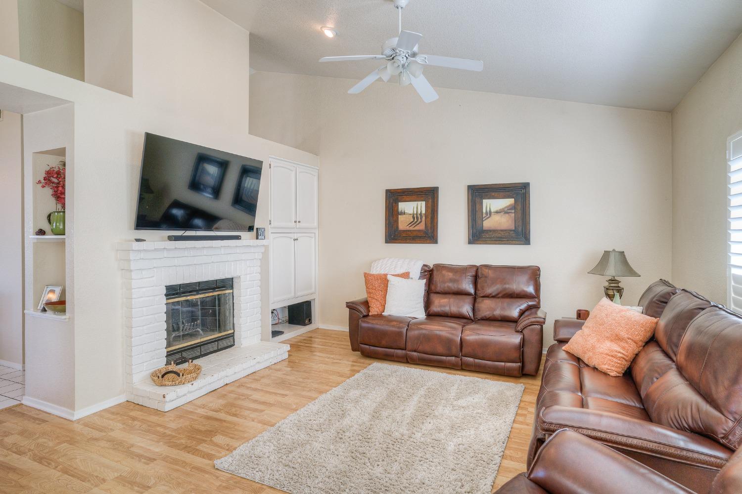 Living room with a white brick fireplace, mounted TV, and brown leather sofas.