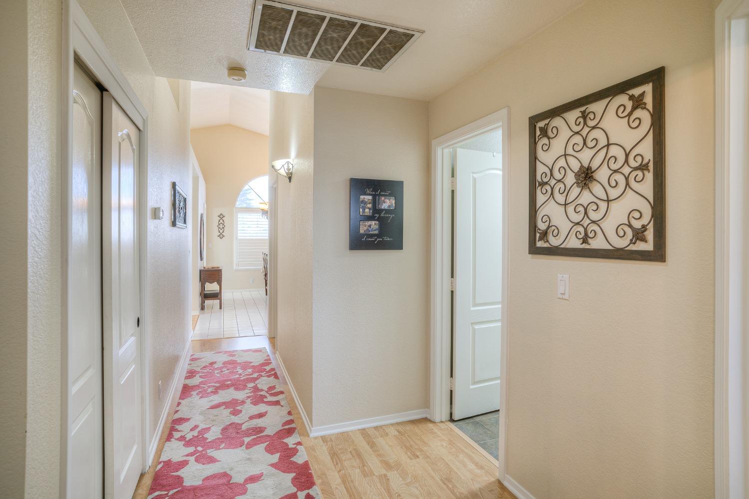 Bright hallway with a red floral runner, white doors, and wrought-iron wall art.