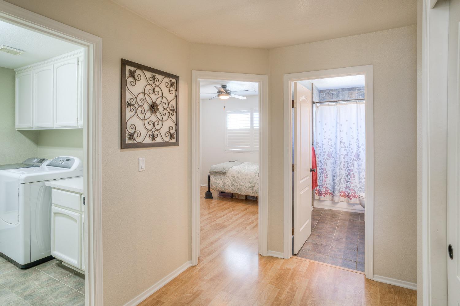 Hallway with a laundry area, bedroom, and bathroom visible through three doorways.