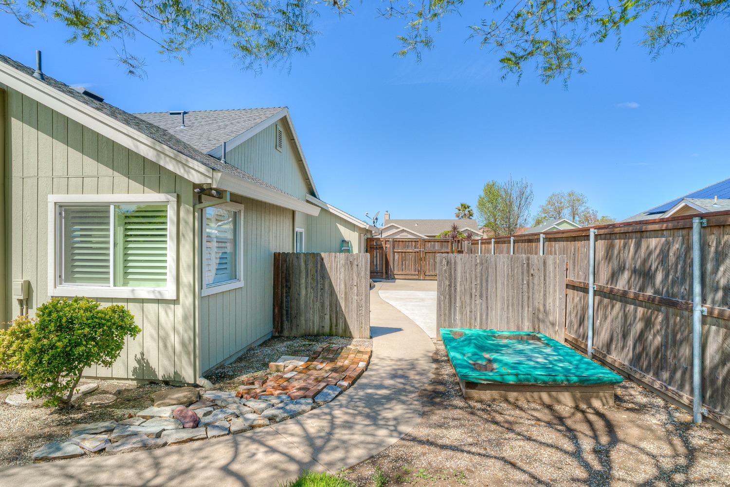 Fenced side yard with a small turquoise pool beside the home and a curved concrete walkway.