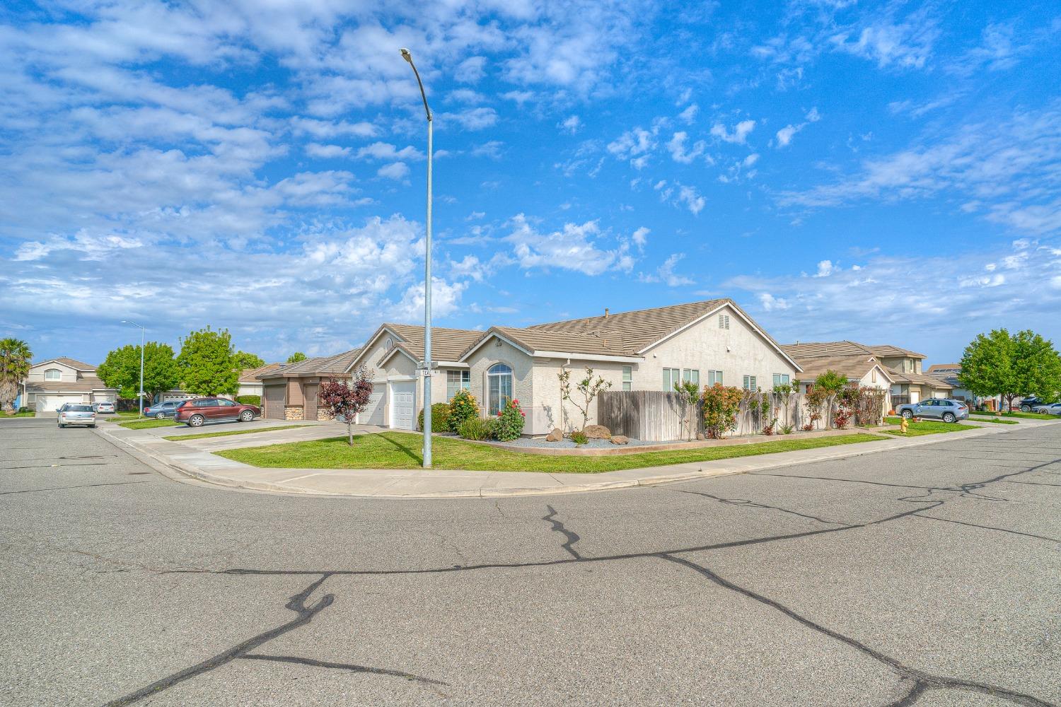 Single-story corner home with a tiled roof, fenced side yard, and landscaped beds.