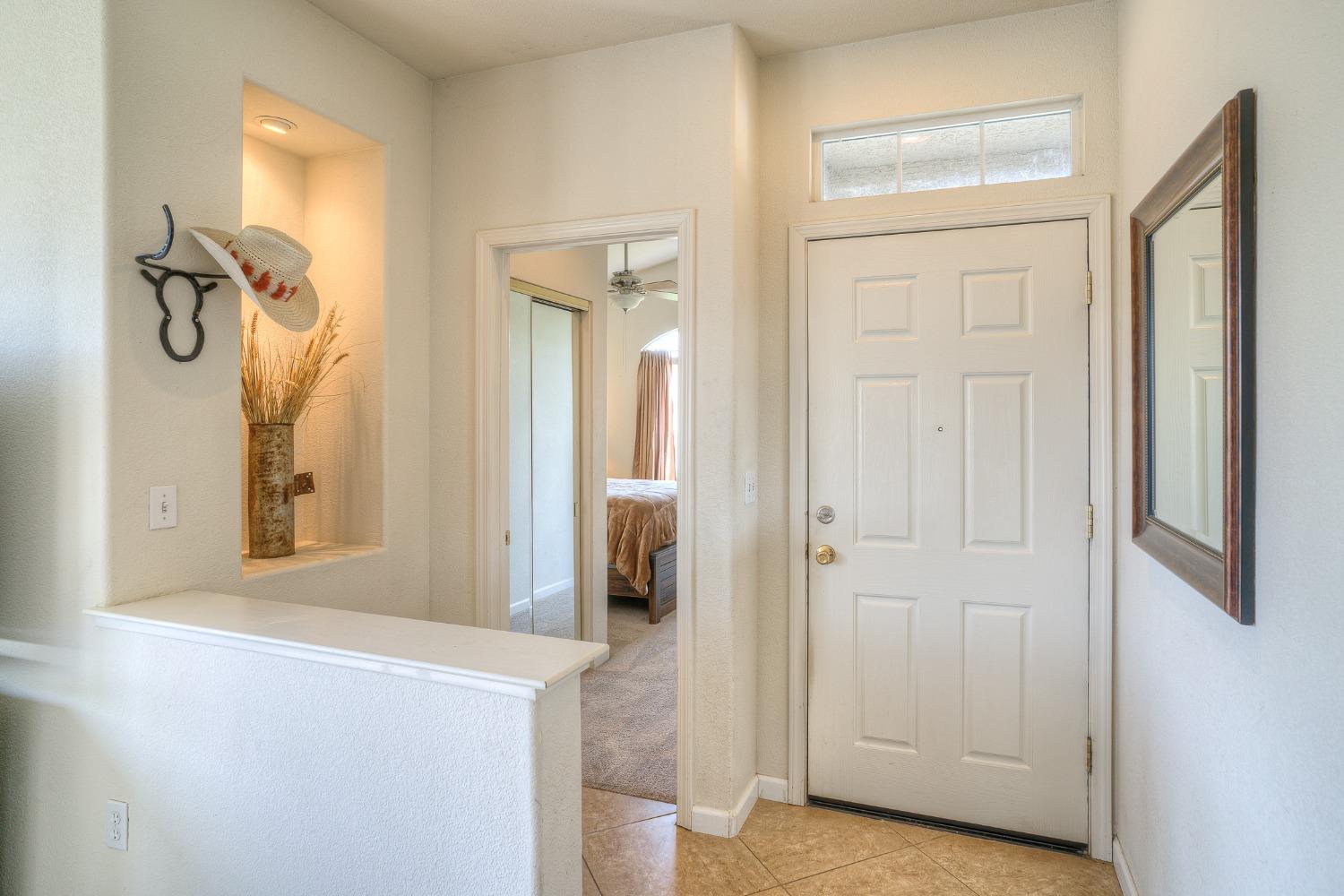 Entry foyer with tiled floor, recessed display niche, and bedroom visible through doorway.