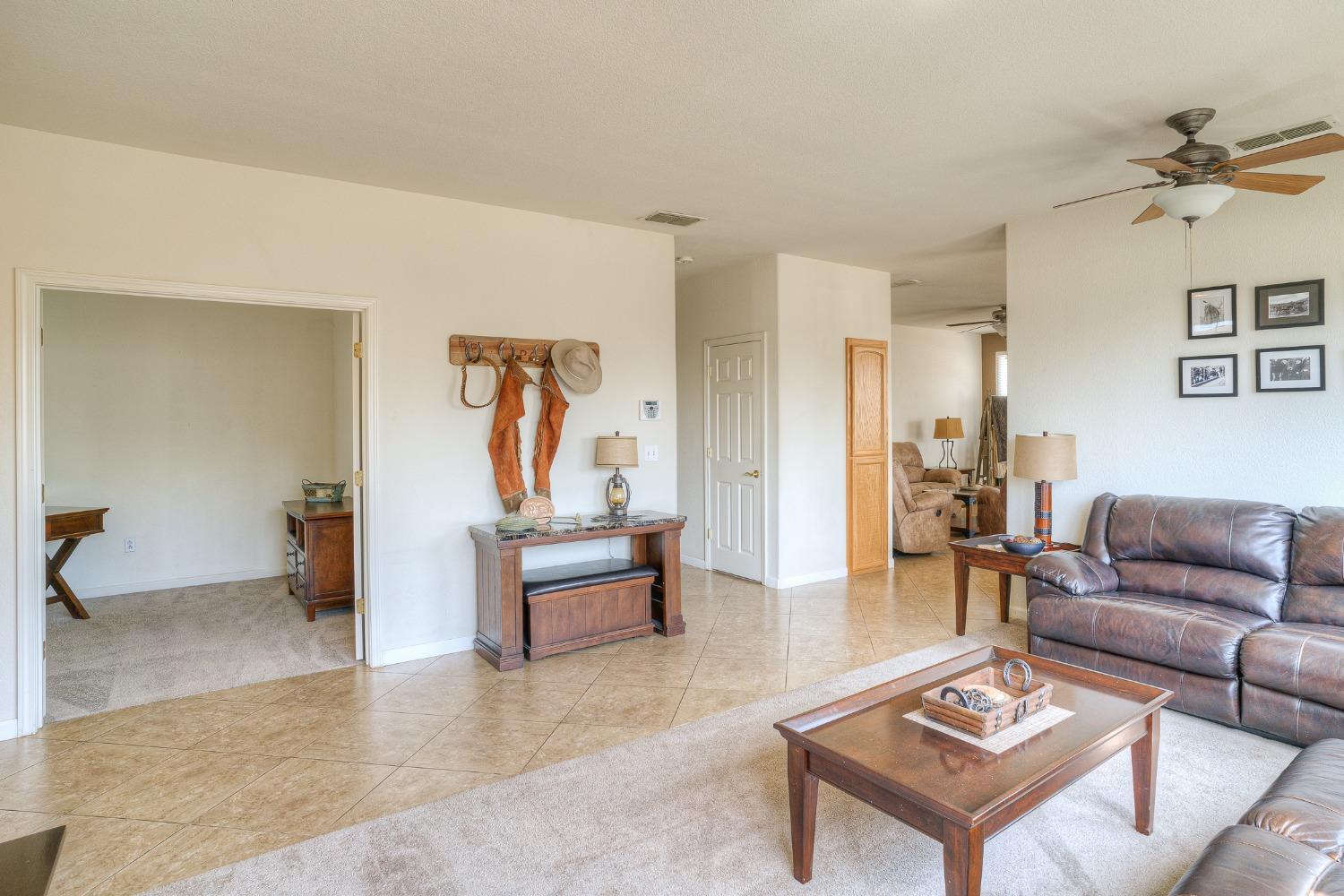 Living room with a brown leather sofa, wooden coffee table, and tiled floor.