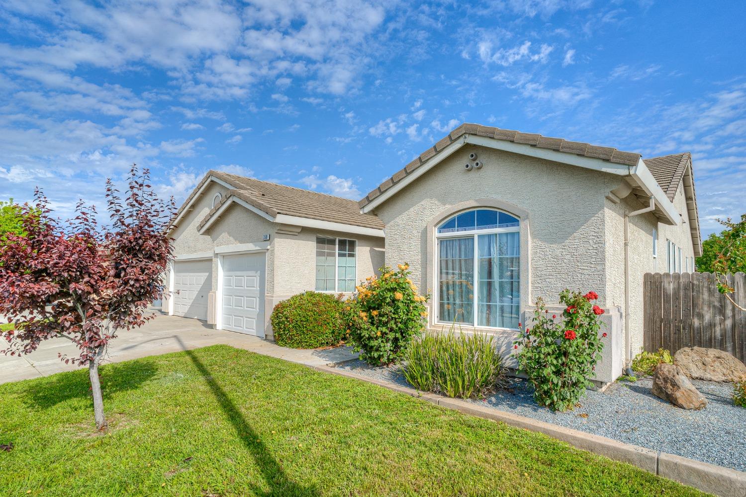 Single-story stucco home with a tiled roof, two-car garage, and arched front window.