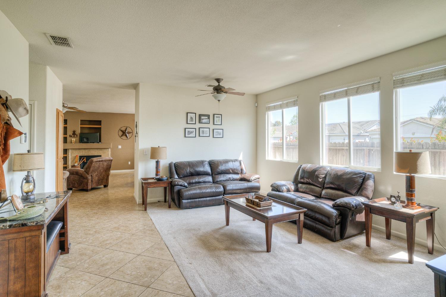 Living room with dark leather sofas, large windows, and an adjoining sitting area.