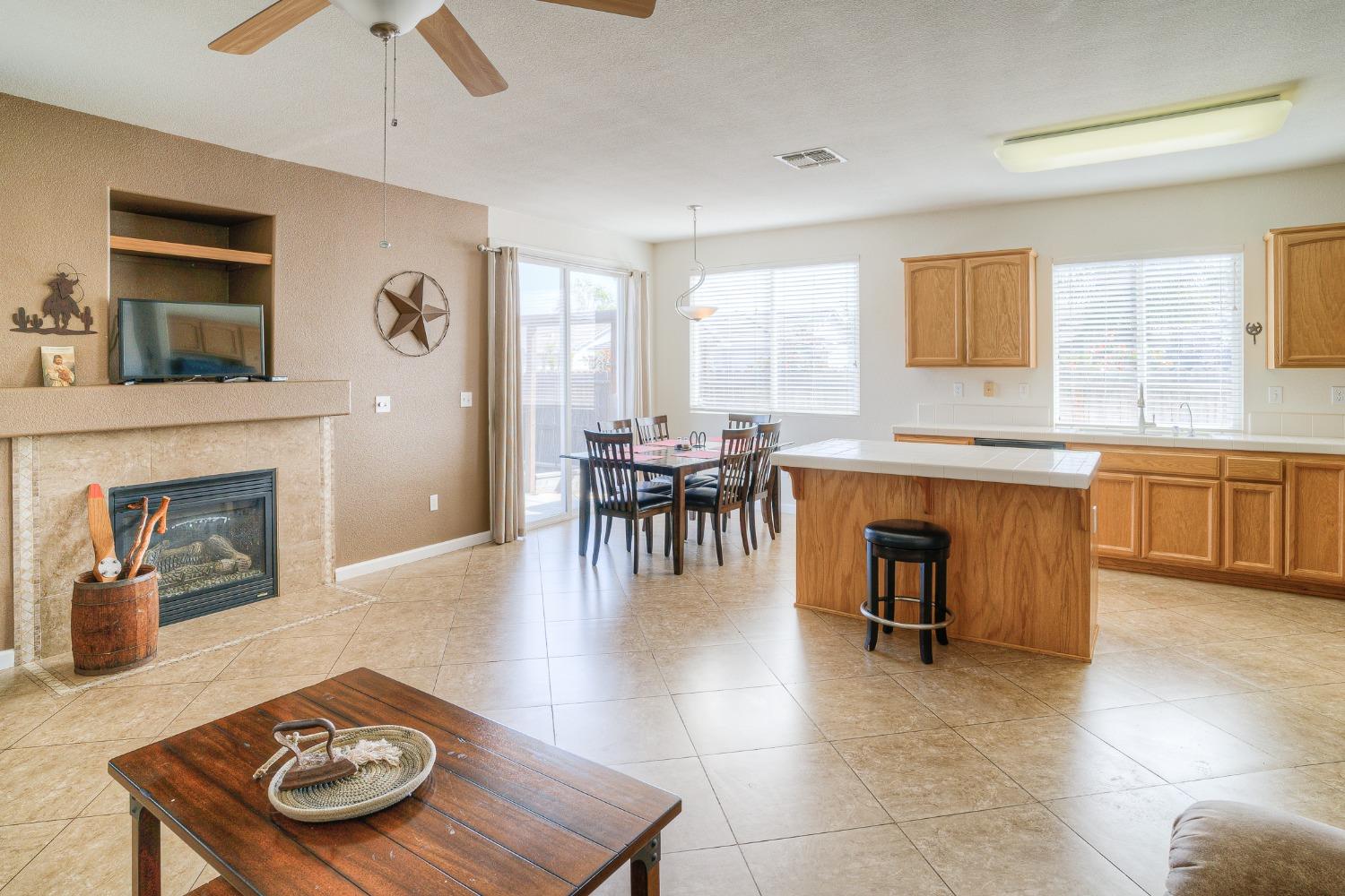 Open kitchen and dining area with a wood island, tiled floors, and an adjoining fireplace.